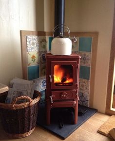 a red stove with a basket next to it on a wooden floor in front of a window