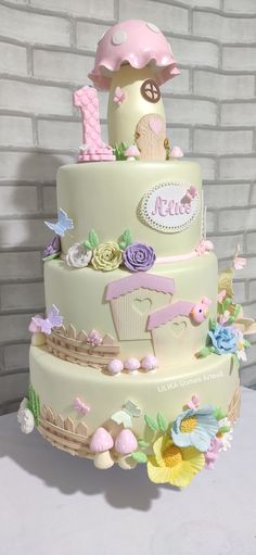 a three tiered cake is decorated with pink and purple decorations, including an umbrella