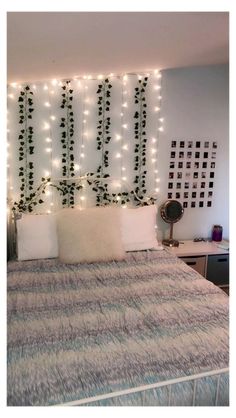 a bed that has some lights on the headboard and pillows in front of it