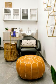 a chair and ottoman in a room with white walls, black flooring and gold accents