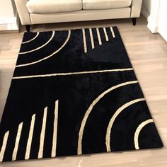 a black rug with white lines on it in front of a couch and coffee table