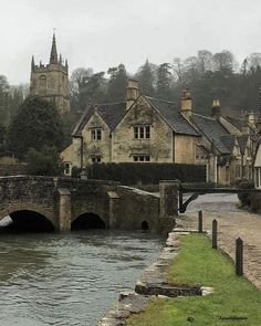 an old stone bridge over a river in the middle of town