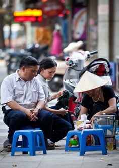 two people sitting on stools in the street