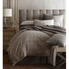 the bed is made up with grey sheets and pillows