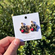 a person holding up a pair of earrings in front of some bushes and trees with the words studio city on it