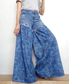 a woman is leaning against a wall with her hand on her hip while wearing blue pants