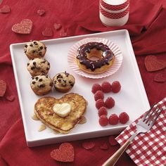 heart shaped pancakes, raspberries and other desserts on a white plate with red napkin