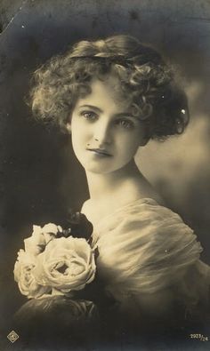 an old photo of a woman with flowers in her hand