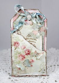 a small card with flowers and butterflies on it, sitting on a white doily