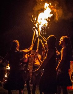 a group of people standing around each other holding sticks in the air with fire coming out of them