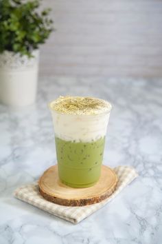 a green drink sitting on top of a wooden coaster