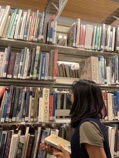 a woman standing in front of a bookshelf filled with lots of different types of books