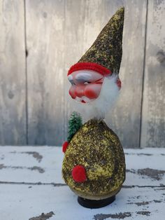 a gnome figurine sitting on top of a rock with a christmas tree in its mouth