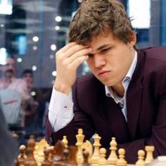 a man sitting at a chess table with his hand on his head and looking down