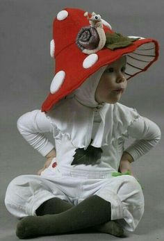 a small child wearing a red hat with white polka dots and a flower on it