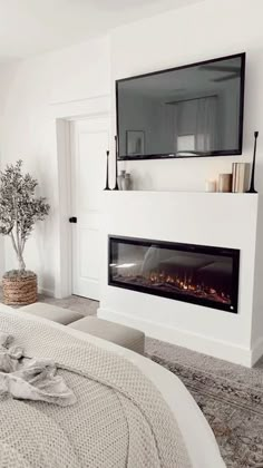 a white bedroom with a fireplace in the corner