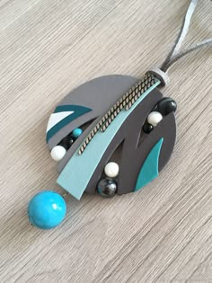 an ornament made out of wood and beads on a wooden table next to a blue ball