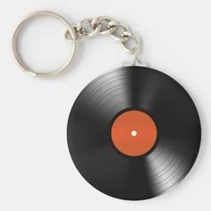 a black record keychain with an orange disk on the front and back side