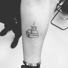 a black and white photo of a cup of coffee on top of some books tattoo