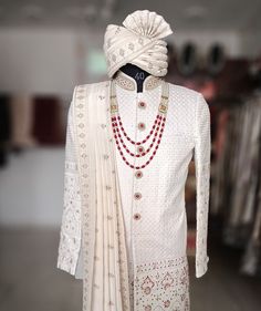 a mannequin wearing a white outfit with red beads