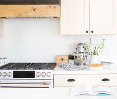 an open book is sitting on the kitchen counter next to the stove and oven top