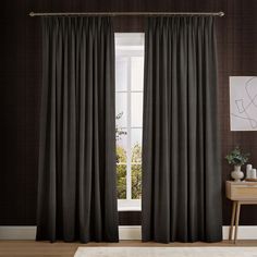 a living room with black curtains and a white rug in front of the window on top of a wooden floor