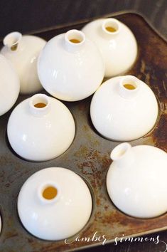 small white vases sitting on top of a pan