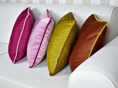 three different colored pillows on a white couch