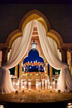 a decorated stage with candles and white drapes