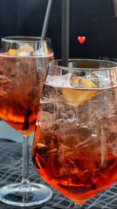 two glasses filled with liquid and ice on top of a table