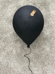 a black balloon on the ground with a string attached to it and a cork in the middle