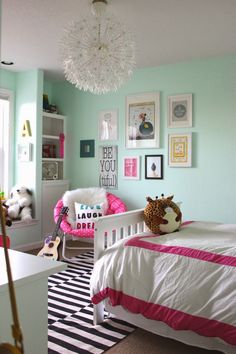 a bedroom decorated in pink and white with pictures on the wall