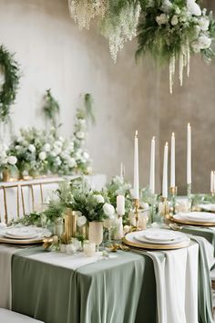 the table is set with candles and greenery for an elegant winter wedding reception in white and green