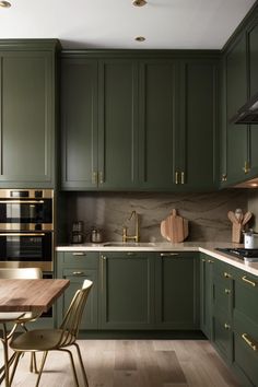 a kitchen with green cabinets and gold handles on the oven, counter tops and chairs