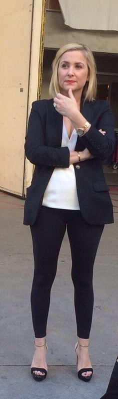 a woman in black and white is standing on the sidewalk with her arms folded out