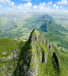 an aerial view of mountains and valleys with green grass on each side, in the foreground is a blue sky