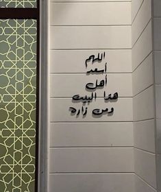 arabic writing on the side of a wall in a public bathroom with tiled floors and walls