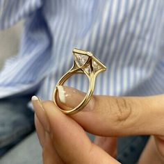 a close up of a person's hand holding a ring with a diamond on it