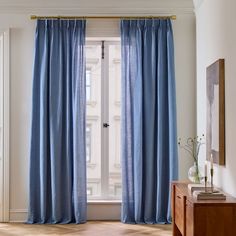 a living room with blue drapes and a wooden table in front of the window