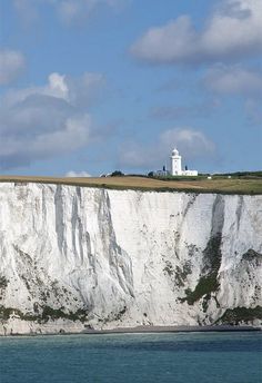 a lighthouse on top of a white cliff next to the ocean