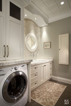 a washer and dryer in a room with white cabinetry, counter tops and drawers