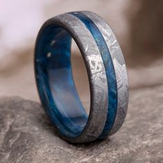 a wedding band with blue and gray wood inlays on top of a rock