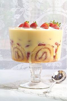 a trifle with strawberries on top in a glass dish next to a spoon