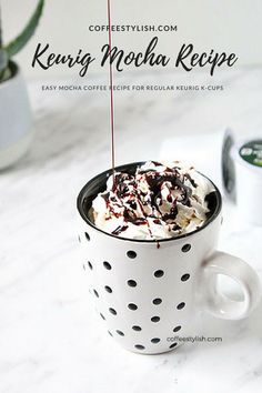 a coffee cup filled with whipped cream and toppings on top of a white counter