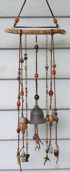 a metal bell hanging from the side of a white building with lots of beads on it