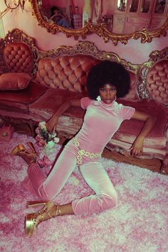 a woman sitting on the floor in front of a couch with pink carpet and gold trimming