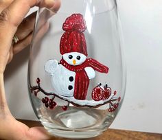 someone is holding up a wine glass with a snowman on it