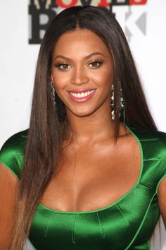 a woman in a green dress posing for the camera with long hair and big earrings