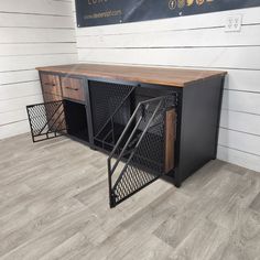 a wooden desk with metal mesh doors and drawers on the bottom, in front of a white wall