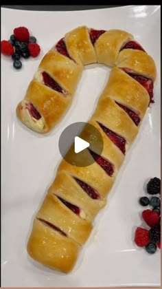 a white plate topped with fruit covered pretzel next to berries and raspberries